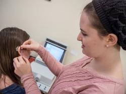 一名听力学学生正在装助听器的照片
