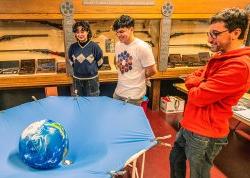 Physics majors Renzo Herrera and Stephanie Montoya with Professor Marc Favata setting up their curved spacetime demo.