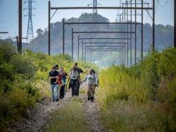 10 people walk on a trail that was once a rail road.