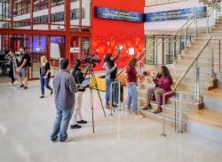 供应链管理 students filming on lobby stairs