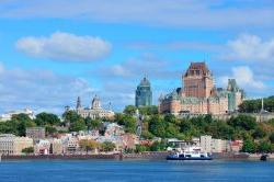 Quebec City skyline over river with blue sky and clouds.
